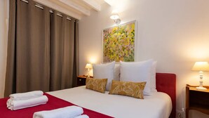 Ein Hotelzimmer mit einem großen Bett, zwei Nachttischlampen, einer roten Tagesdecke und einem Gemälde an der Wand.