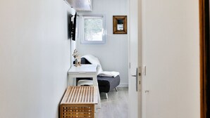 A narrow hallway with a wooden floor, a white radiator, a wooden bench, a desk with a chair, and a bed. - Immodreams - Le Vivace - Avoriaz (Avoriaz)
