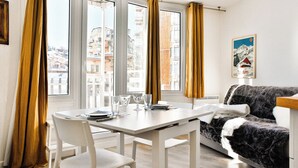A modern living room with a white table and chairs, a sofa, and large windows with curtains. - Immodreams - Le Vivace - Avoriaz (Avoriaz)