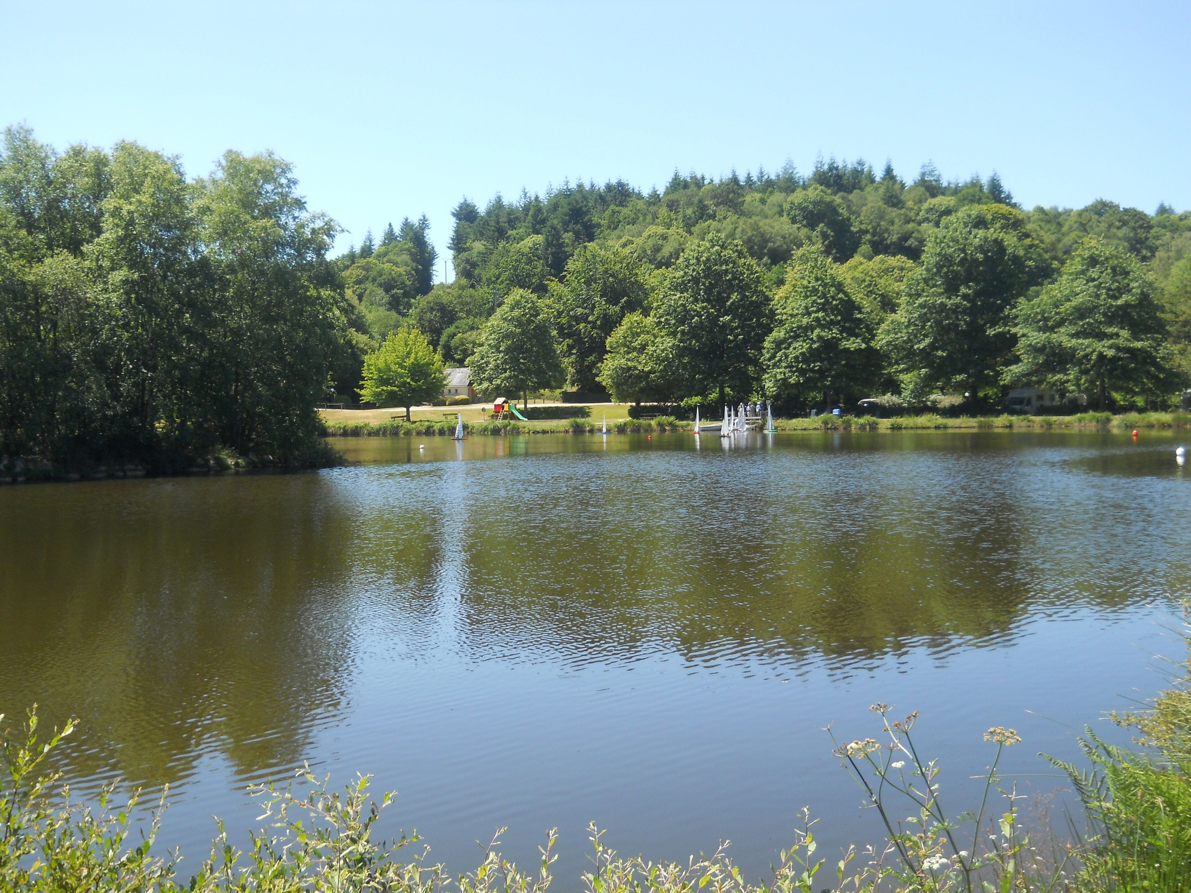 A serene lake with a playground and a boat in the water.