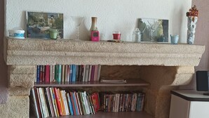 A cozy reading nook with a fireplace, a bookshelf, and a dining area.