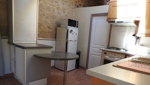 A compact kitchen with a refrigerator, microwave, stove, and a small table.