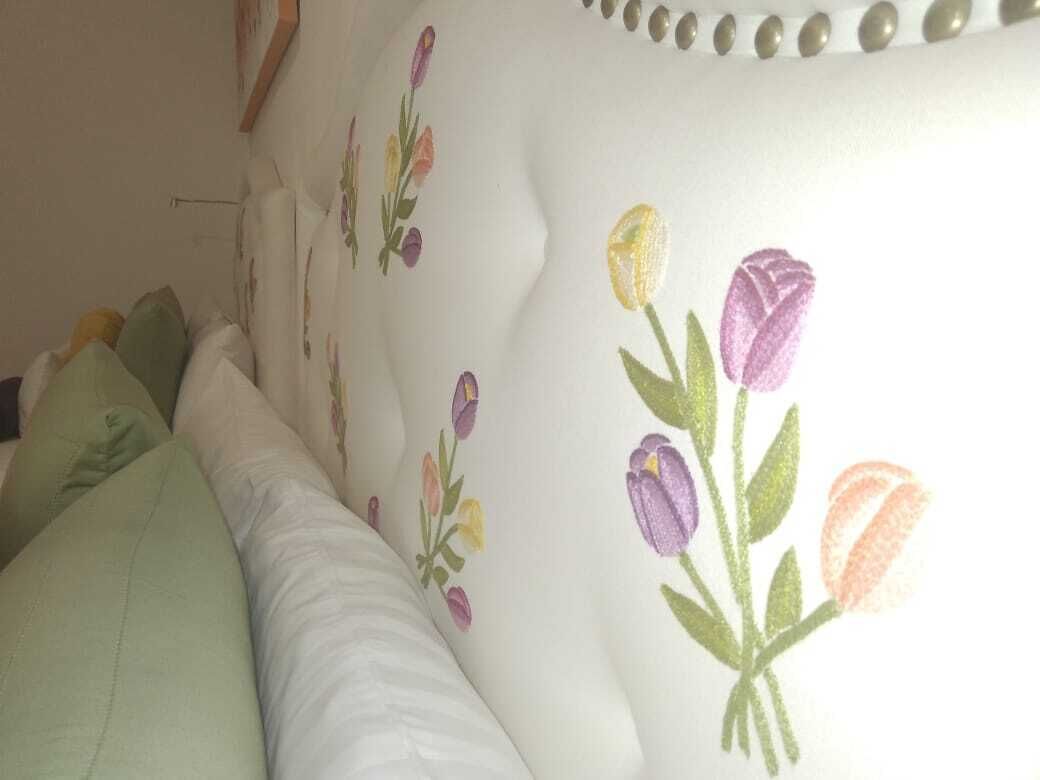 A bed with a floral-patterned headboard and pillows.