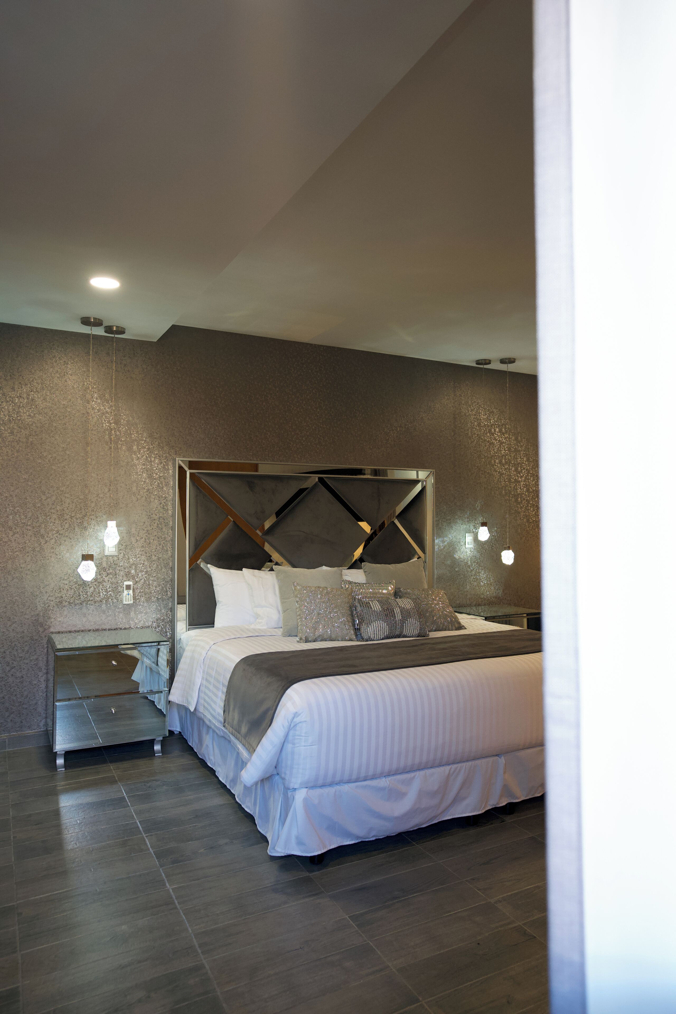 Een moderne slaapkamer met een groot bed, een nachtkastje en een wandlamp.
