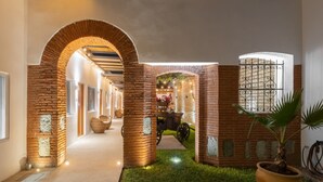 A corridor with brick arches, a potted plant, and a window with decorative bars. - ArcoSodi Hotel Boutique (Oaxaca)