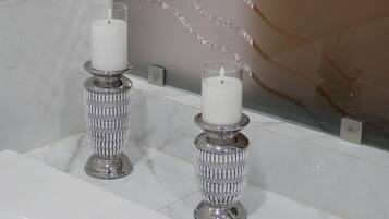 A bathroom with two ornate candle holders on a marble sink.
