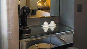 A modern bathroom with a large mirror, a black coffee machine, and a plush chair. - ArcoSodi Hotel Boutique (Oaxaca)