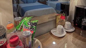 A hotel room with two beds, a minibar, and a dining area with a tray of snacks and drinks. - ArcoSodi Hotel Boutique (Oaxaca)