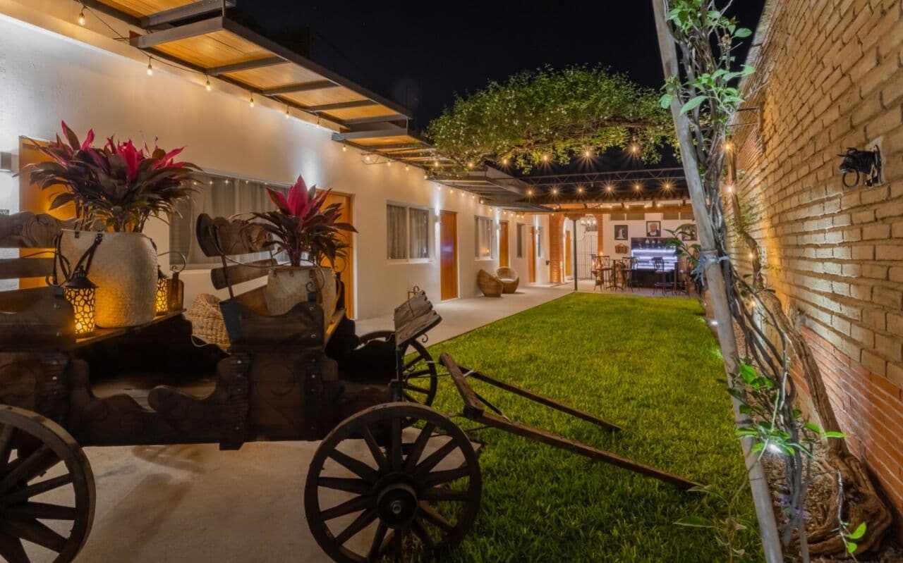 A well-lit outdoor area with a grassy lawn, a wooden cart, and potted plants.