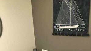 Ein Bett mit gestreifter Bettwäsche, ein kleiner Nachttisch mit Lampe und ein Wandbild mit einem Segelboot.