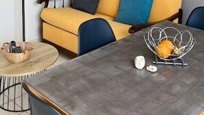 Ein modernes Wohnzimmer mit einem gelben Sofa, blauen Kissen, einem runden Couchtisch und einer Stehlampe.