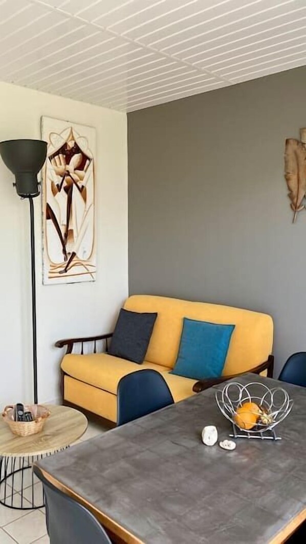 A modern living room with a yellow sofa, blue cushions, a round coffee table, and a floor lamp.