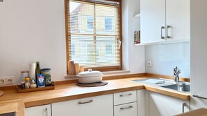 A kitchen with a window, wooden countertop, white cabinets, and a sink.