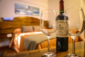 Two empty wine glasses on a wooden table with a bottle of wine behind them. - Hotel Royal Princess (Mendoza)
