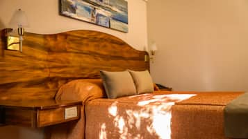 A neatly made bed with a wooden headboard, a bedside table with a lamp, and a painting on the wall.