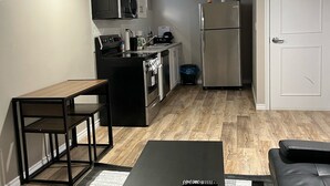 A compact living space with a kitchenette, a dining area with a table and chairs, and a sofa.