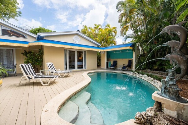 A swimming pool with lounge chairs, a hot tub, and a dolphin sculpture. - BE STILL- 4 Bedroom, 3 Bath with POOL & Guest Cottage (Key West)