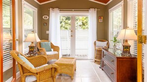 A cozy room with wicker furniture, a ceiling fan, and a view through a glass door. - BE STILL- 4 Bedroom, 3 Bath with POOL & Guest Cottage (Key West)