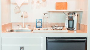 A kitchen with a coffee maker, wine glasses, and a water pitcher.