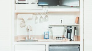 Une petite cuisine équipée d’un four à micro-ondes, d’une machine à café et d’un petit réfrigérateur.