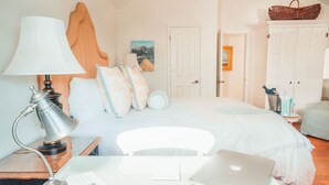 A bedroom with a bed, a desk with a laptop, a lamp, and a wardrobe.