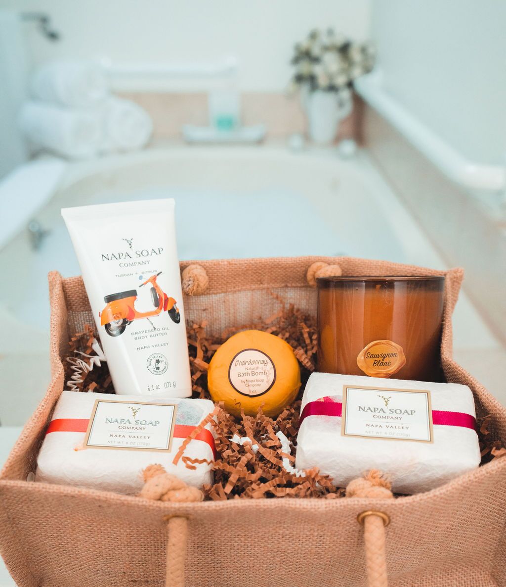 Un cesto regalo con diversi prodotti per la spa, tra cui una crema corpo, una bomba da bagno e delle candele.