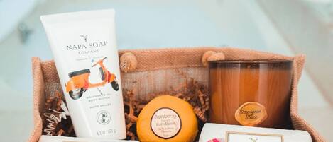 Un cesto regalo con diversi prodotti per la spa, tra cui una crema corpo, una bomba da bagno e delle candele.