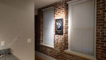 A hallway with brick walls, white-framed windows, and a framed photo on the wall.