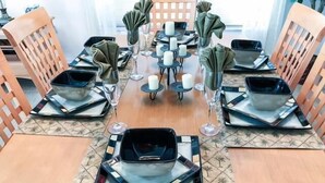 Une table à manger dressée avec des assiettes carrées, des verres et des serviettes.