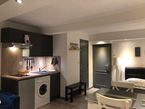 A compact hotel room with a kitchenette, a washing machine, a small dining table, and a bed. - Cosy Studio Proche Palais Des Papes (Avignon)