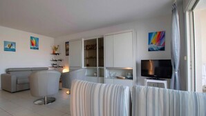 A modern living room with a sofa, armchair, and a flat-screen TV. - Apartment With Balcony And View On The Port. (Fréjus)