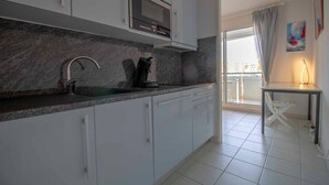 A modern kitchen with white cabinets, a granite countertop, and a built-in microwave. - Apartment With Balcony And View On The Port. (Fréjus)