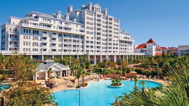 Un hotel grande con varias plantas, piscina y zonas verdes alrededor.
