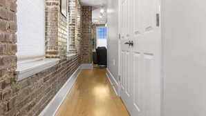 A hallway with exposed brick walls, a wooden floor, and white doors.