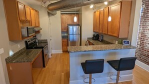 A modern kitchen with wooden cabinets, granite countertops, stainless steel appliances, and a central island with bar stools.