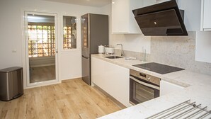 A modern kitchen with a built-in oven, a sink, and a stainless steel trash bin.