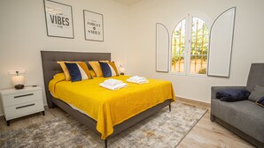 A bedroom with a bed, bedside tables, a chair, and a window with a view.