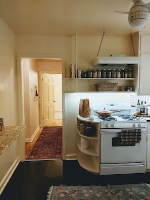 Compact kitchen with a stove, pot rack, and storage for essentials.