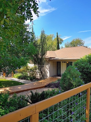 Surrounded by lush greenery, this single-story house offers an outdoor space with a covered deck.