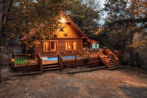 Escape to a secluded forest retreat with a cozy cabin, porch, and serene pool.
