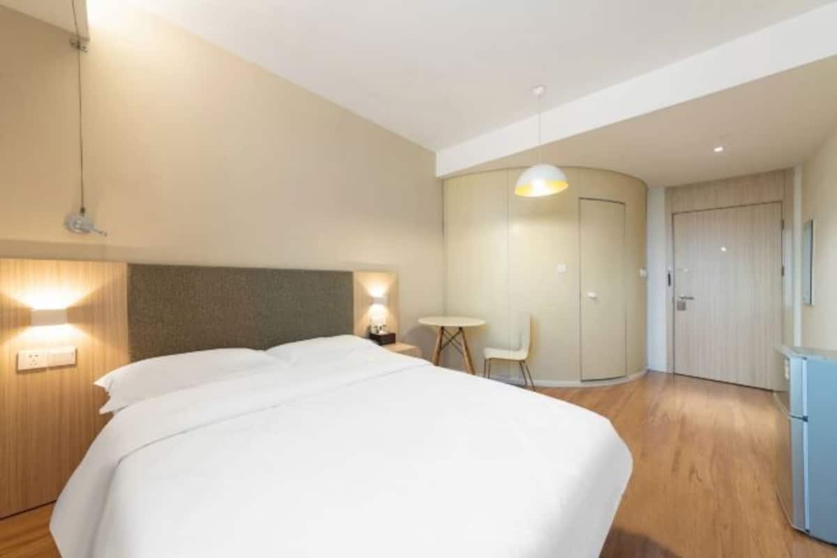 A hotel room with a large bed, bedside tables, a desk, and a chair.