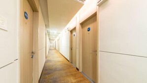 A hotel hallway with wooden doors, a patterned carpet, and a long corridor. - Lianjia Holiday Hotel (Jigang Senior High School) (Jinan)