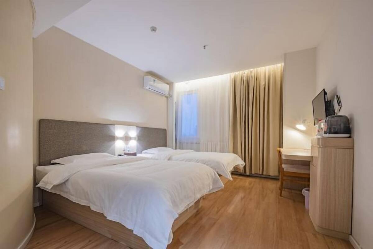 A hotel room with two beds, a desk, and a chair.