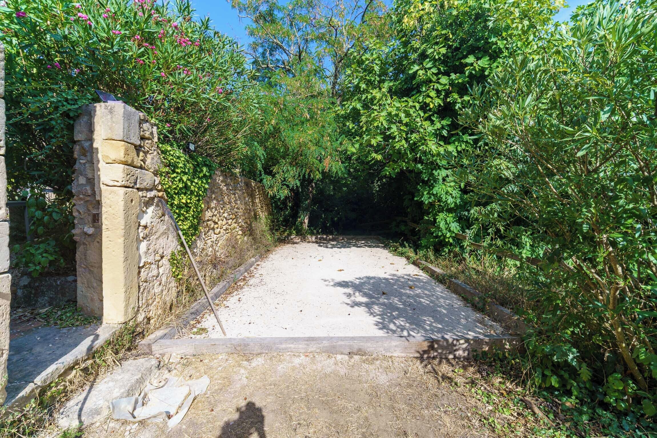 A stone structure with a narrow pathway leading through dense foliage.