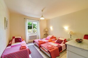 A room with two beds, a window with curtains, a desk with a lamp, and a small table with a bowl. - Mas Provence (Uzès) - Luxury Apartment - swimming pool 12-6 m - 9 acres garden (Tresques)