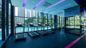 A modern gym with treadmills, exercise bikes, and a large window overlooking a pool and cityscape. - Ascott Star KLCC Kuala Lumpur (Kuala Lumpur)