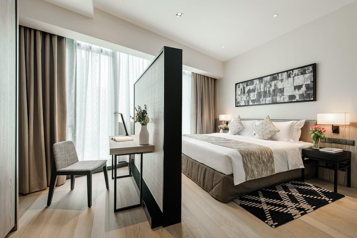 Moderni hotellihuone, jossa on suuri sänky, työpöytä ja tuoli.