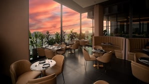 A rooftop restaurant with tables and chairs, large windows, and a view of the city skyline. - Ascott Star KLCC Kuala Lumpur (Kuala Lumpur)