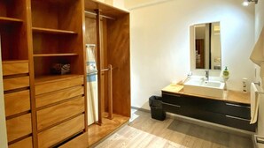 Une salle de bain moderne avec un meuble-lavabo en bois, un grand miroir et un dressing spacieux doté de nombreuses étagères.