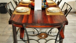 Une table à manger avec six chaises, une bouteille et des assiettes posées sur une nappe.